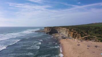 ribeira d'ilhas strand, klippor och atlanten hav vågor på solig dag. portugal. antenn se. Drönare rör sig framåt- och uppåt video