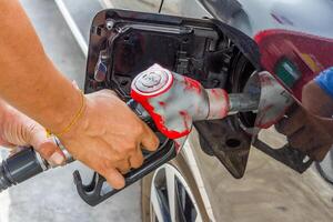 hombres sostener combustible boquilla a añadir combustible en coche foto