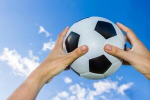 holds a soccer ball in the sky on blue sky photo