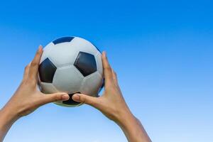 holds a soccer ball in the sky on blue sky background. photo