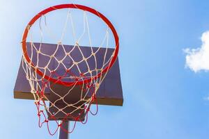 Outdoor basketball hoop with blue sky and clouds photo