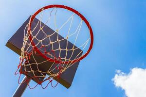 Outdoor basketball hoop with blue sky and clouds photo