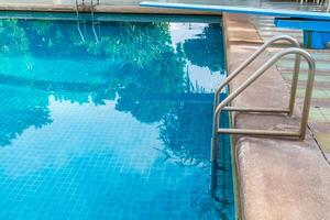 Escalera de barras de apoyo en la piscina azul foto