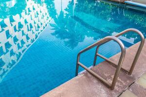 Escalera de barras de apoyo en la piscina azul foto