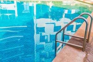 Escalera de barras de apoyo en la piscina azul foto