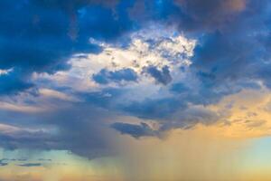 Dainty wispy pale salmon pink and golden yellow clouds at sunset and raining photo