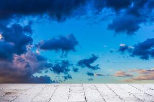 Dainty wispy pale salmon pink and golden yellow clouds at sunset with cement floor photo