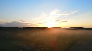 un mágico puesta de sol terminado el aldea, dónde el niebla desciende. puesta de sol desde aéreo vista. un calina de niebla en el Dom. un globo es en el horizonte video