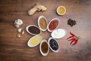 Sauces and spices. A set of popular sauces and spices on a wooden background. photo