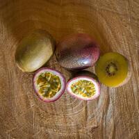 Juicy of passion fruit and kiwi on a wooden background photo