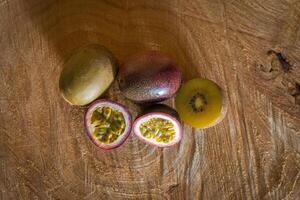 Juicy of passion fruit and kiwi on a wooden background photo