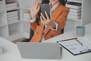 mujer de negocios asiática que usa una computadora portátil y trabaja en la oficina con un documento de calculadora en el escritorio, planificando el análisis del informe financiero, la inversión del plan de negocios, el concepto de análisis financiero. foto