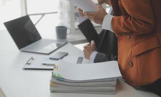 Asian Businesswoman Using laptop computer and working at office with calculator document on desk, doing planning analyzing the financial report, business plan investment, finance analysis concept. photo