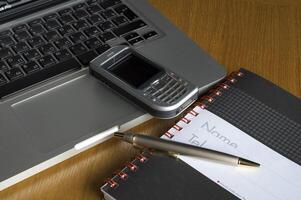 Phone, laptop and empty notebook on the desk photo