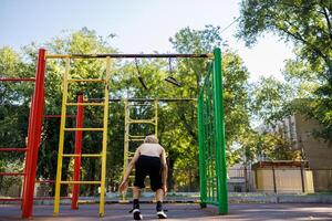 A sports child performed with a jump from the crossbar. Street workout on a horizontal bar in the school park. photo