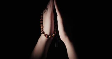 Young Woman Kneeling In The Dark Praying With A Rosary In Her Hands video