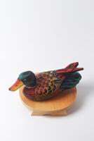 A typical Indonesian duck toy sits on a round wooden board photo