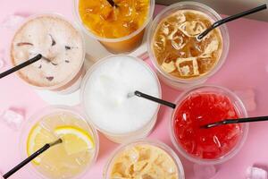 Takeaway glasses of summer drinks with ice close up. Lemonades and coctails top view photo