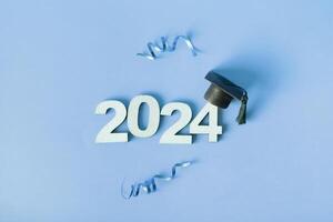 Class of 2024 concept. Wooden number 2024 with graduated cap and confetti photo