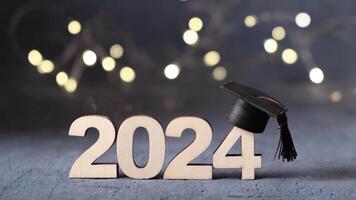 Class of 2024 concept. Number 2024 with graduation cap and bokeh lights. photo
