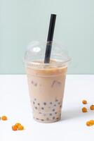 Plastic glass with bubble tea and ice. Trendy summer drink on colourful background photo