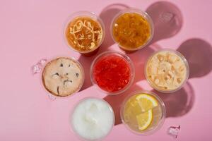 Colourful summer drinks with ice top view. Lemonades and coctails on pink background photo