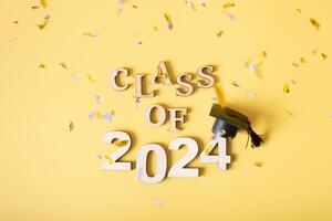Class of 2024 concept. Number 2024 with graduated cap on yellow background with tinsel photo
