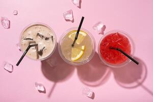 Three takeaway glasses of summer drinks with ice top view. Lemonade on colored background photo