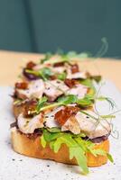 Toast with veal and sun-dried tomatoes, pesto sauce, garnished with peas microgreens photo