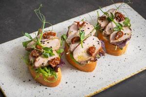 Toast with veal and sun-dried tomatoes, pesto sauce, garnished with peas microgreens photo