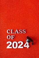 Class of 2024 text with graduation cap on glitter background. Graduation holiday concept. photo