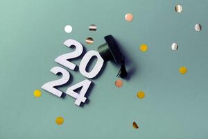 Wooden number 2024 with graduation cap and confetti. Class of 2024 concept photo