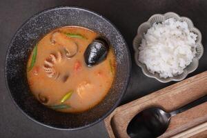 Tom yum soup with seafood and rice ondark background top view photo