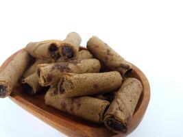 Chocolate wafers rolled in a wooden bowl isolated on white background. A delicious snack that tastes sweet and crunchy photo