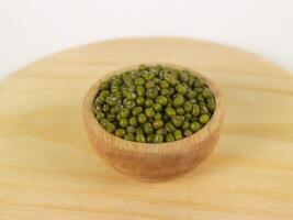 Green raw mung beans in wooden bowl on wooden and white background photo