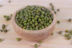 Green raw mung beans in wooden bowl on wooden and white background photo