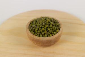 Green raw mung beans in wooden bowl on wooden and white background photo