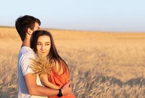 joven hombre abrazando su Novia en puesta de sol en trigo campo. Copiar espacio, amar, unión concepto. foto