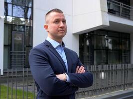 Businessman adopts a confident posture, hands crossed at chest. Businessman displays a calm, commanding presence in elegant business attire. The stance of the Businessman projects assured leadership photo