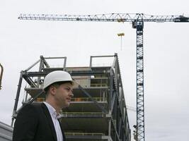 Professional glance Architect with white helmet, business suit, engages deeply with blueprints. The focus of this architect captures the essence of architect commitment to detail close-up photo