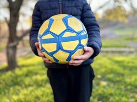 Close up of football boy player holding soccer ball on field of outdoors photo