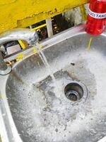 a dirty sink with a yellow and red bottle photo