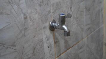 a faucet on a wall with a gray tiled wall photo