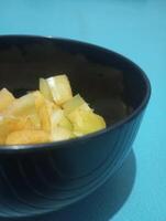 a bowl of sliced fruit on a blue surface photo