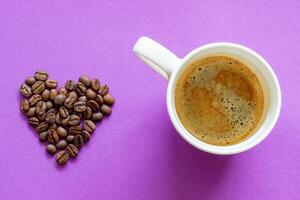 white cup of hot coffee, coffee beans on a pink purple background photo