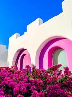 clean deep blue sky, a pink and white building with purple flowers in front photo