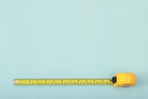 The yellow measuring tape for the mason is placed on a blue background. Soft focus. photo