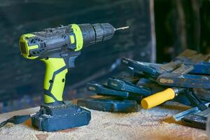 Electric drill,screwdriver on a plywood wooden surface with sawdust in workshop photo