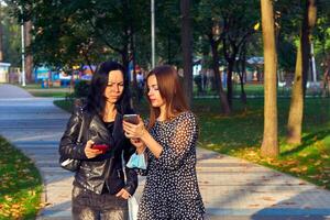 Two girlfriends, young women discussing the news, looking at the phone photo