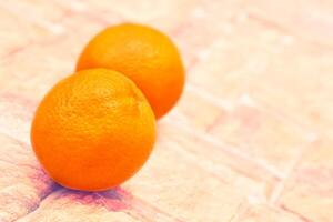 Two ripe sweet juicy oranges on light brown cobblestone photo